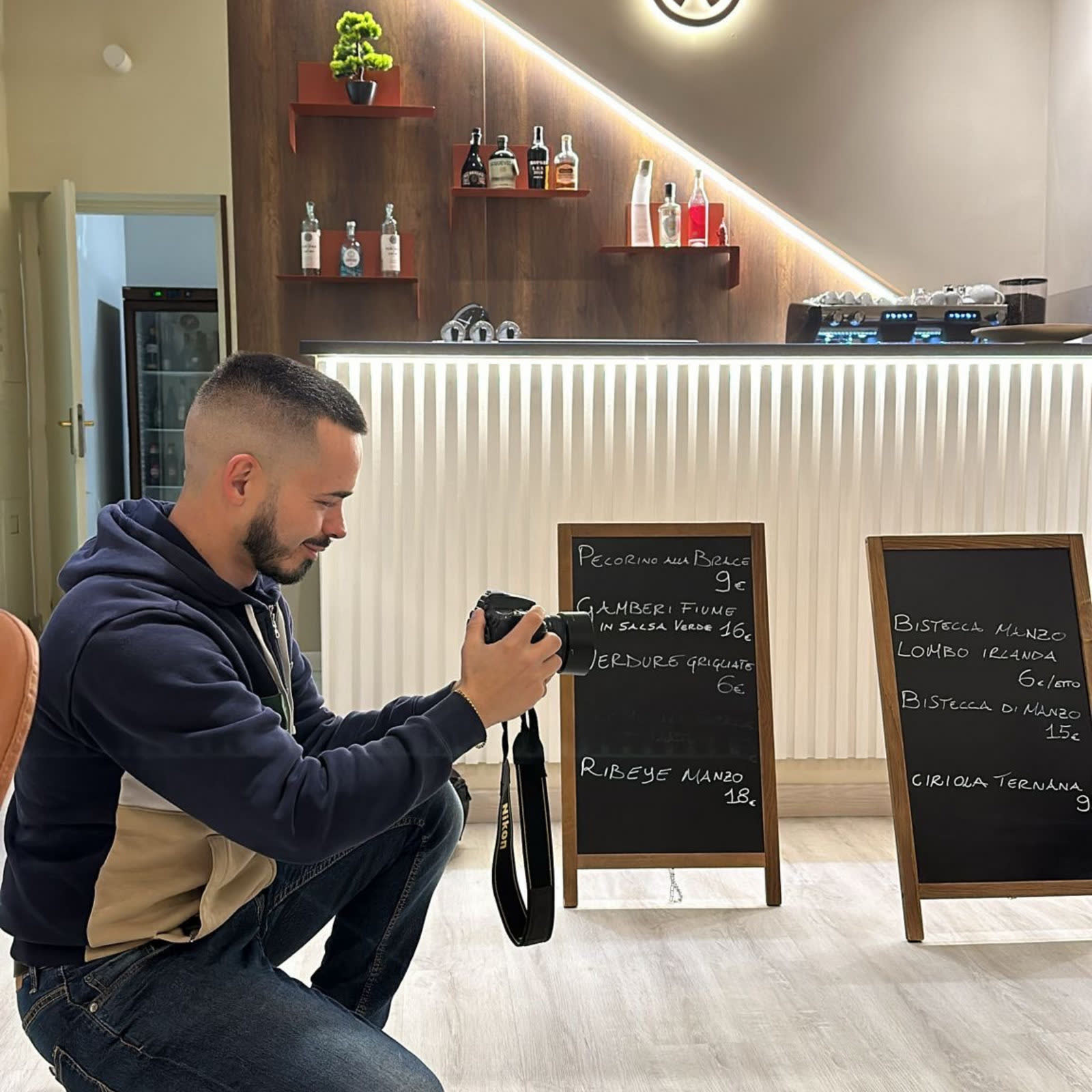 Michele Mattioni scatta una foto in un locale, accovacciato con la macchina fotografica