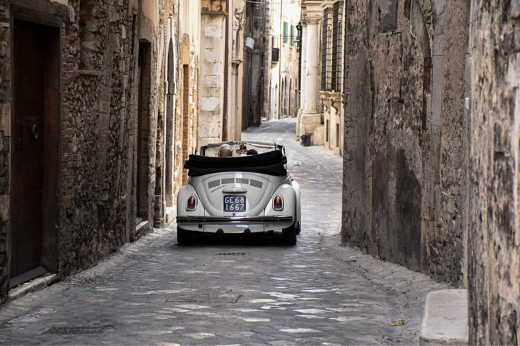Auto d'epoca bianca in un vicolo di pietra