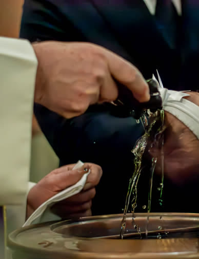 Mani che versano l'acqua del battesimo